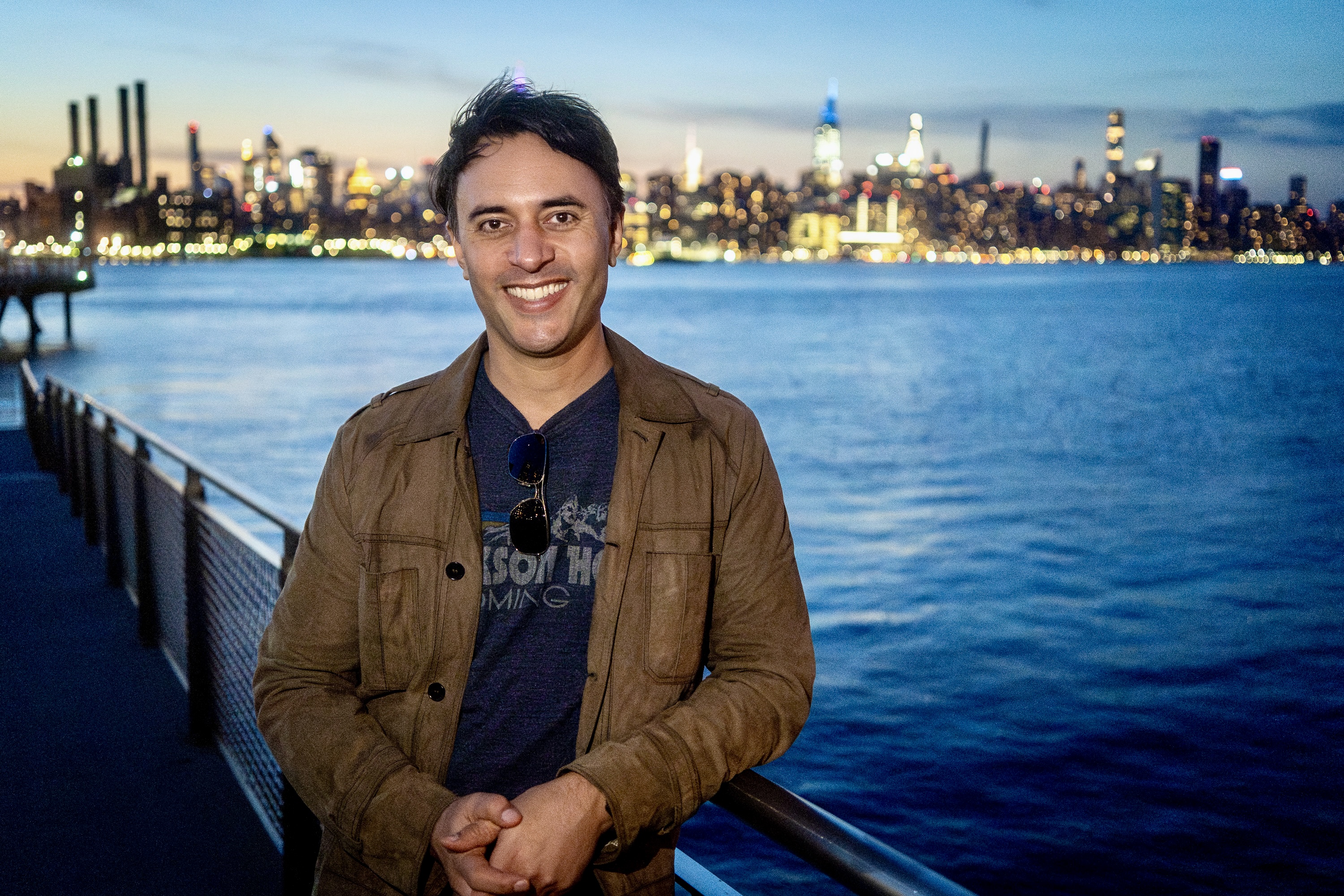 Jay Dixit beside the East River with the Manhattan skyline behind him